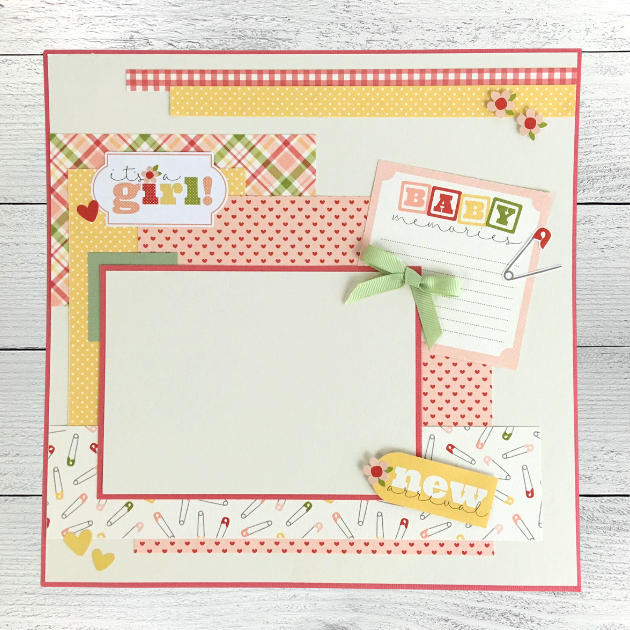 12x12 It's A Girl Baby Scrapbook Page Layout with hearts, a pretty plaid, flowers, safety pins, a journaling card, and a cute green bow
