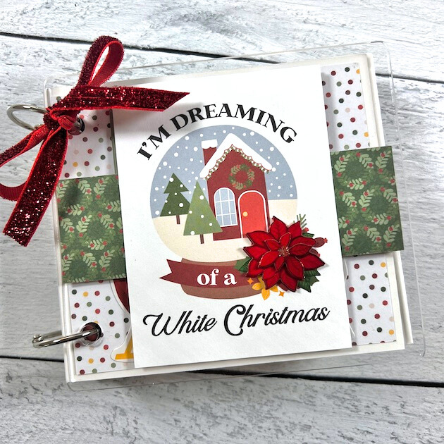 White Christmas Scrapbook Album with snow, trees, poinsettia flowers, a cute house, and wreaths