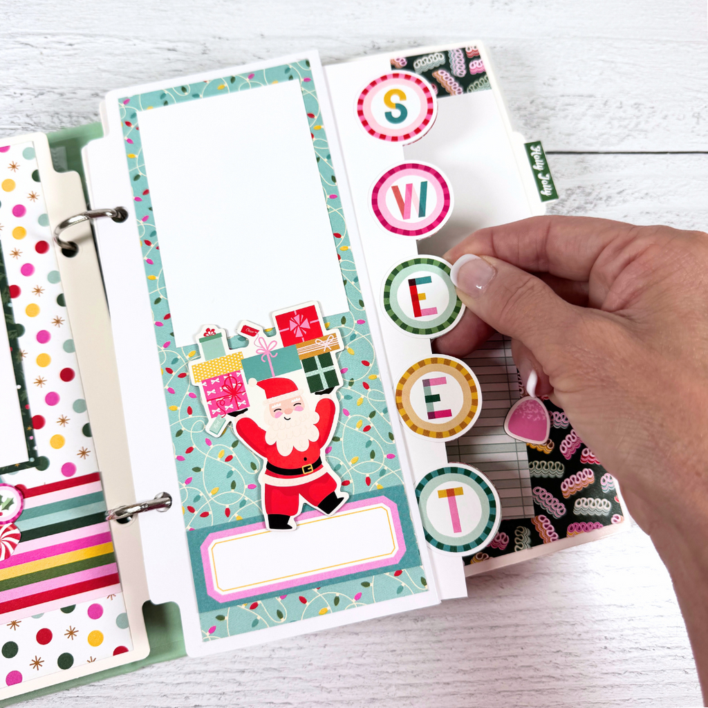 Christmas 25 Scrapbook Mini Album Page with Santa Claus, presents, colorful string lights, and a pocket
