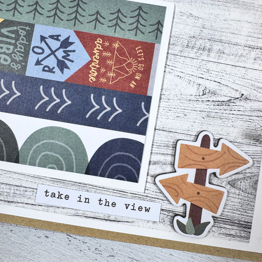 Say Hello To New Adventure Mini Scrapbook Page with arrows, trees, and a wood grain paper