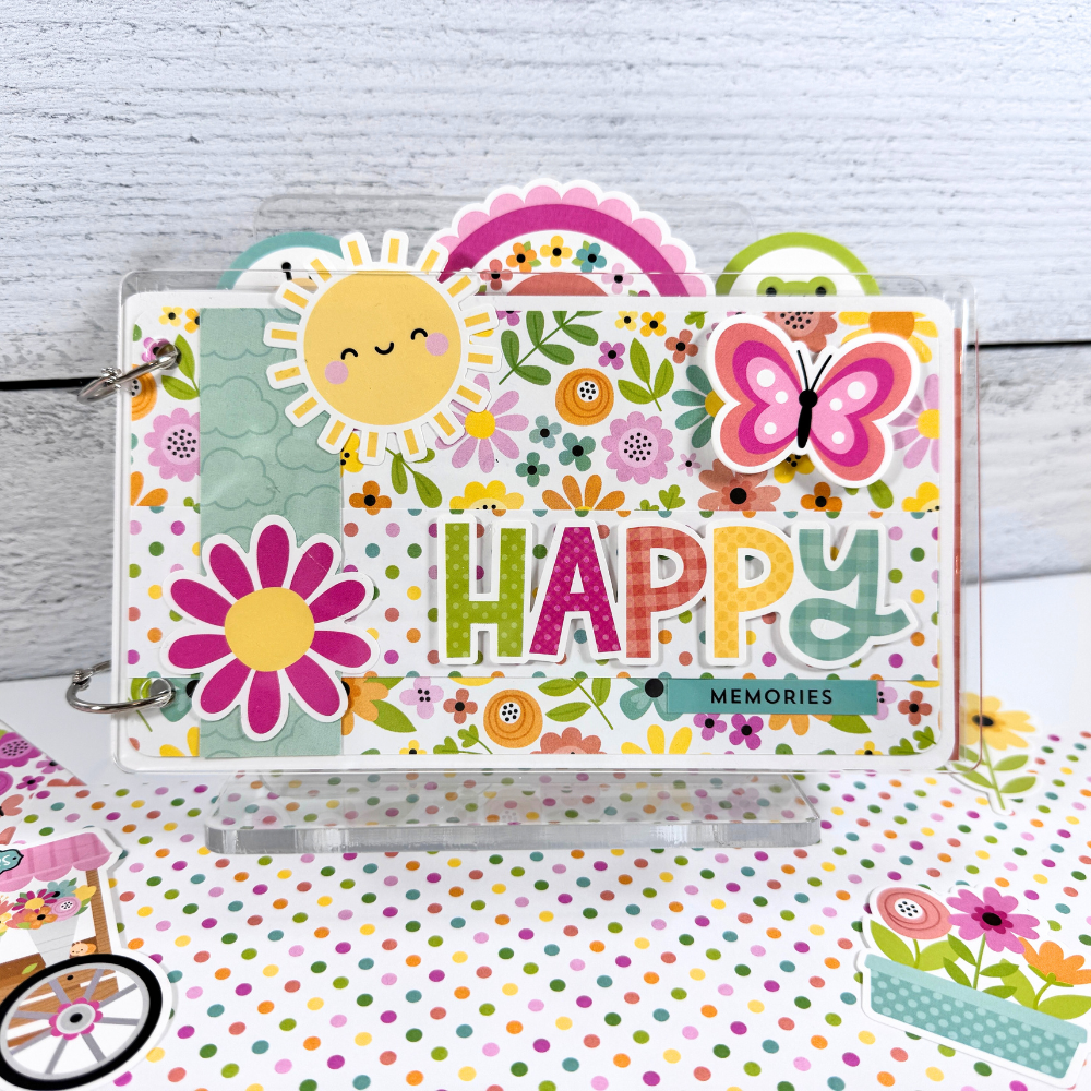 Happy Memories Scrapbook Mini Album by Artsy Albums sitting on a clear acrylic display stand