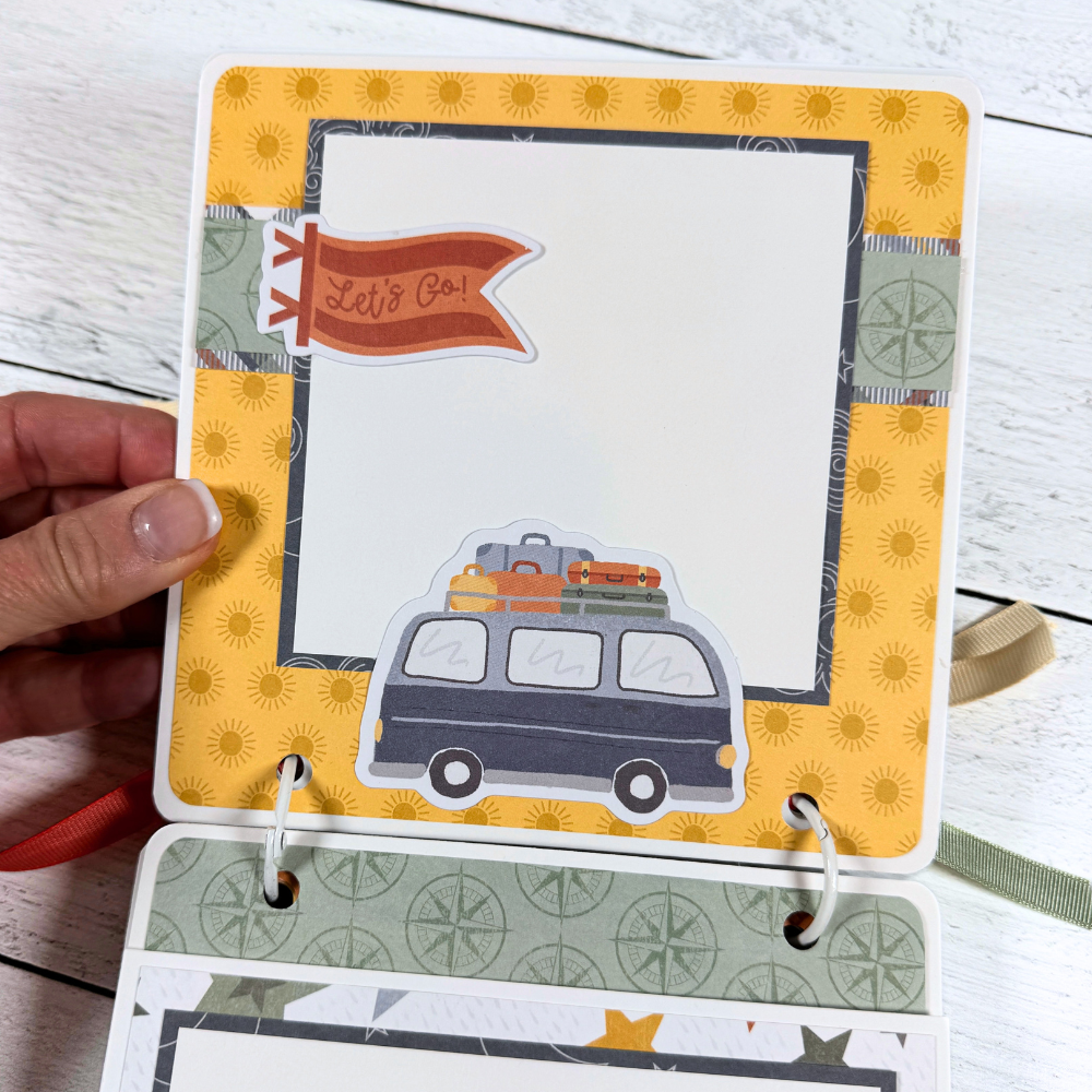 Adventure Scrapbook Mini Album Page with yellow sunshine, compasses, a flag, and a van with luggage