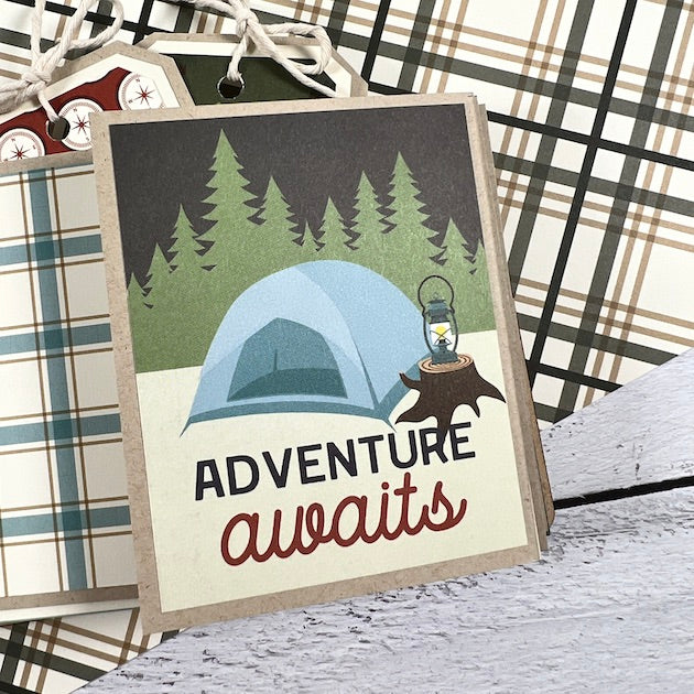Outdoor camping scrapbook album page with a folding element, trees, a tent, and a lantern