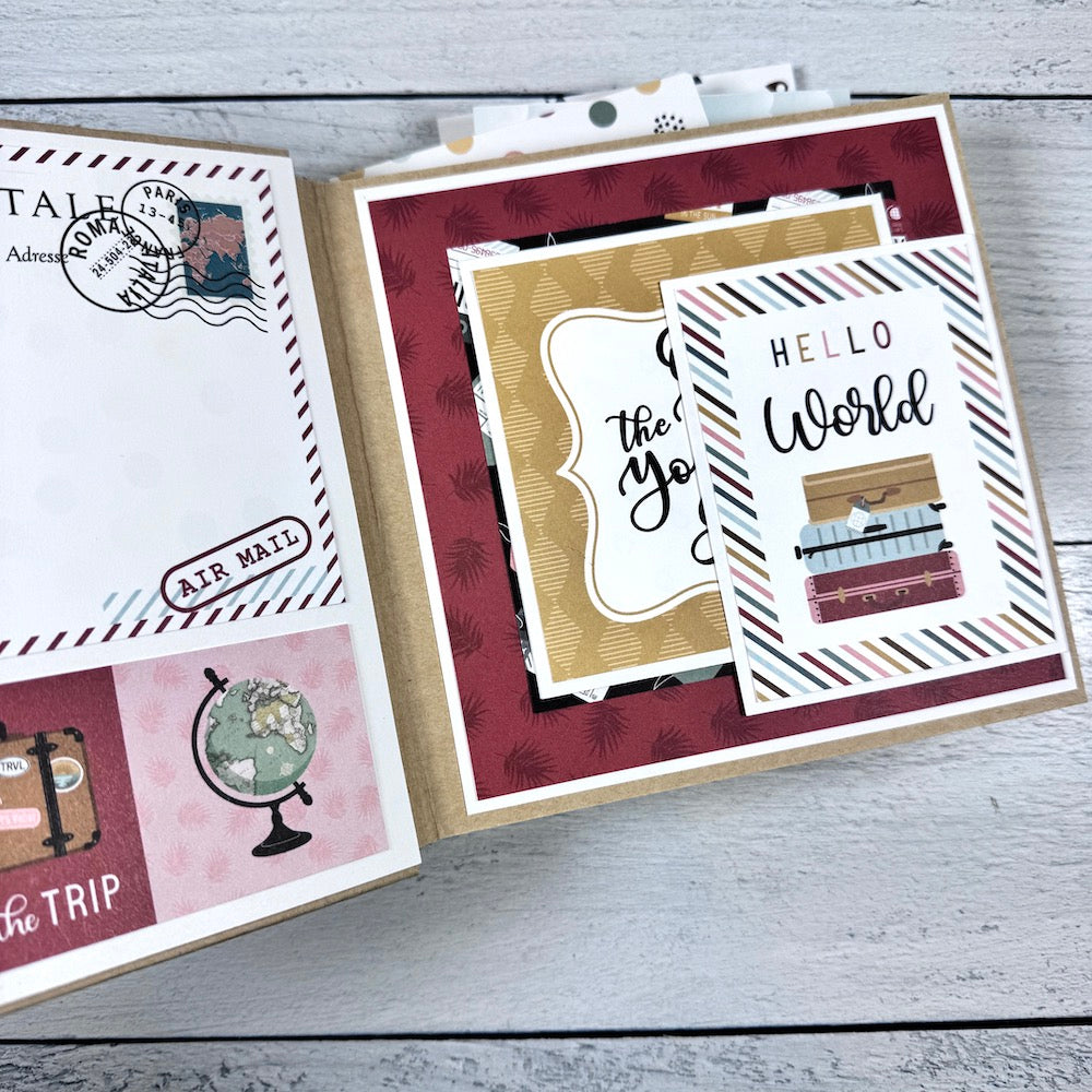 Travel The World With Me Scrapbook Album page with a globe, suitcases, a folding card, and travel stamps