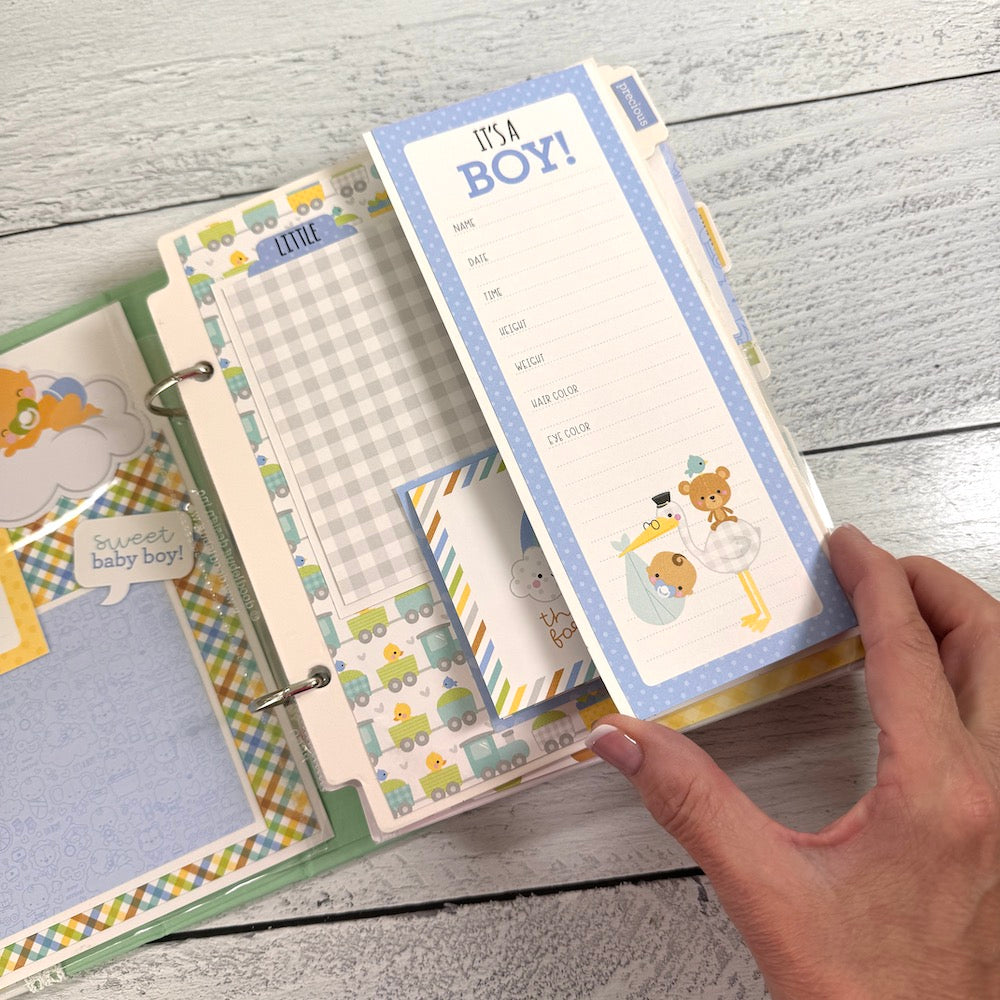 My Baby Boy Scrapbook Album page with a a cute journaling card, plaid paper, a stork, a cute bear, and trains