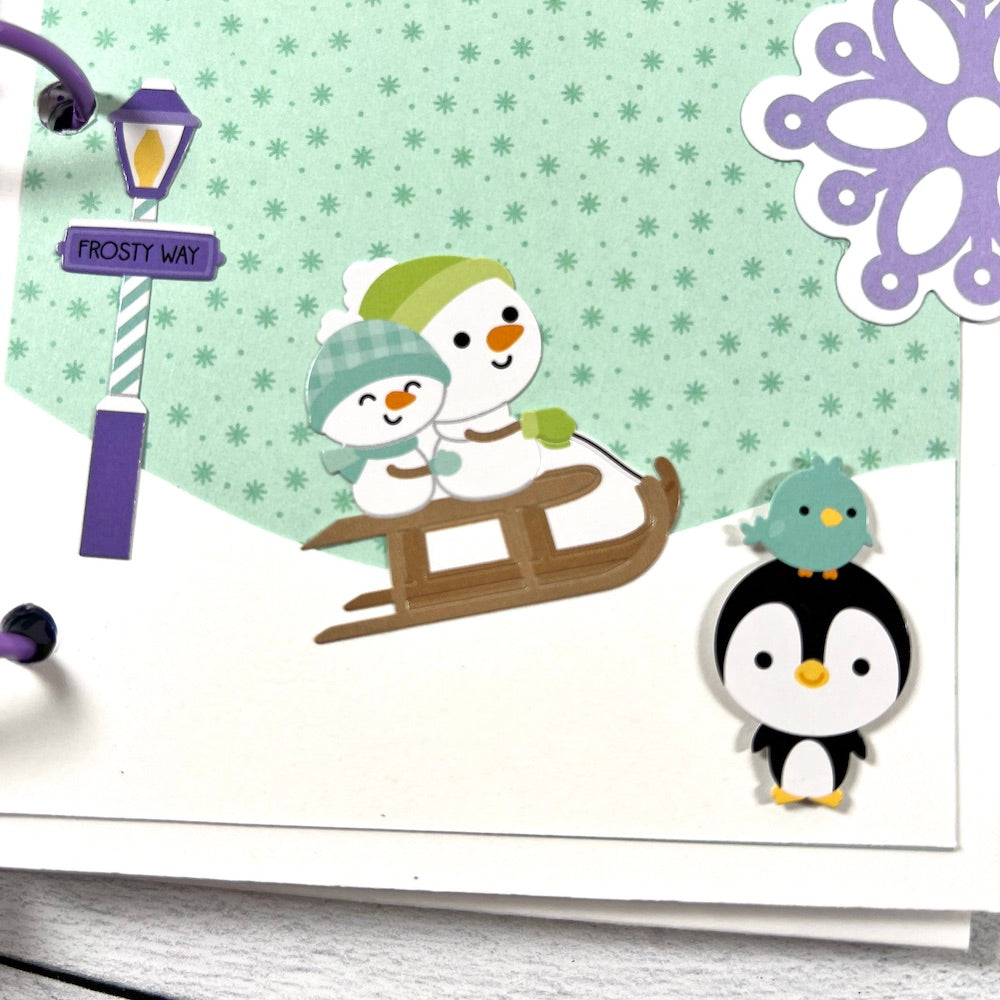 Snow Day Winter Scrapbook Mini Album page with snowflakes, snowmen on a sled, a penguin, and a little bird