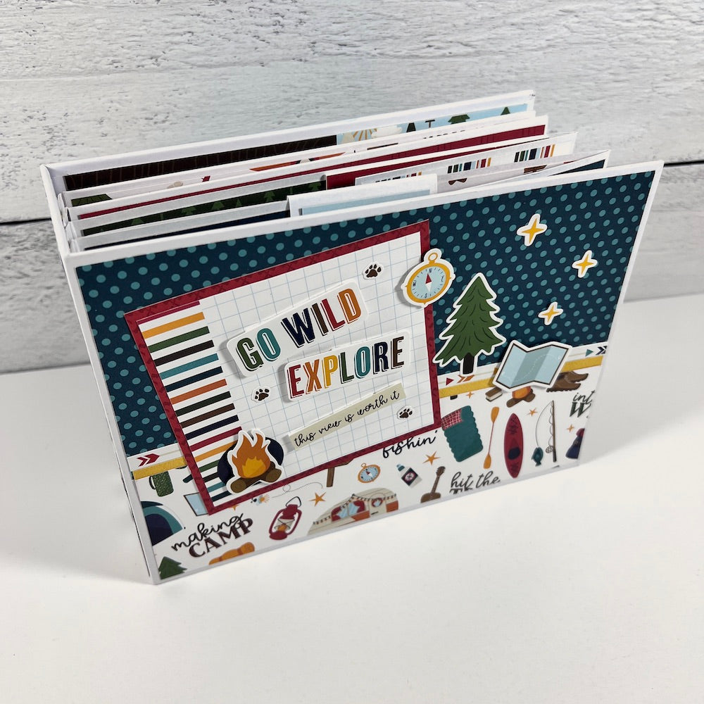 Go Wild Explore Scrapbook Mini Album with camping supplies, trees, and stars