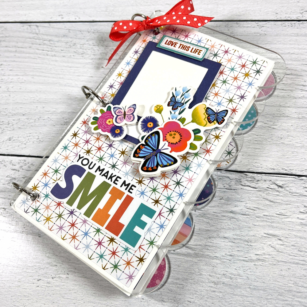 You Make Me Smile Scrapbook Mini Album with a scalloped edge, butterflies, flowers, stars, gold foil accents, and a bow