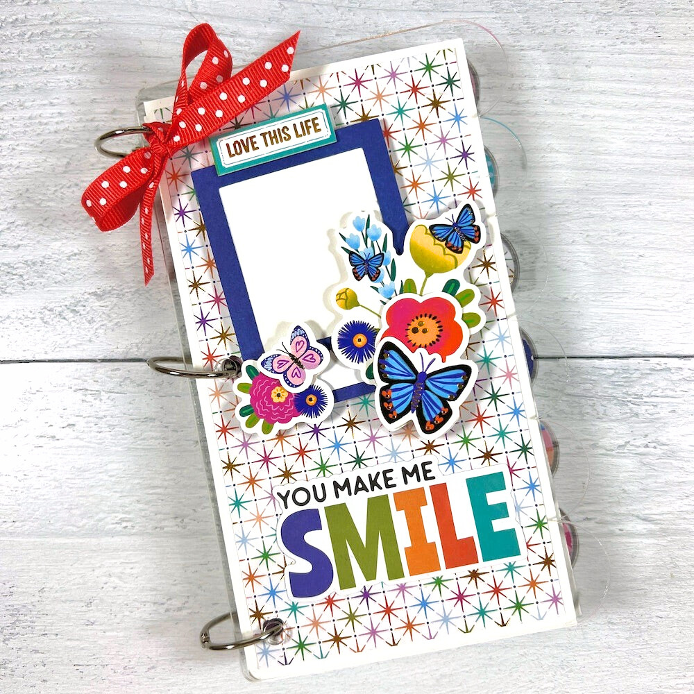 You Make Me Smile Scrapbook Mini Album with a scalloped edge, butterflies, flowers, stars, gold foil accents, and a bow