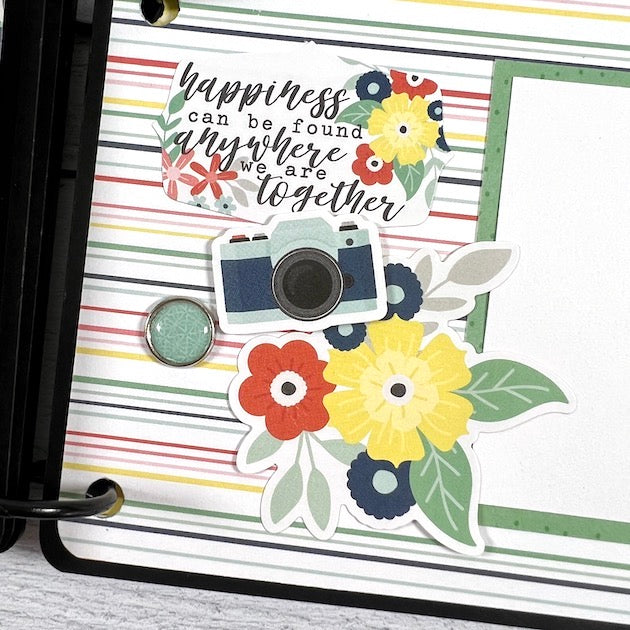 Camera shaped travel scrapbook album page with flowers, a camera, and an enamel brad