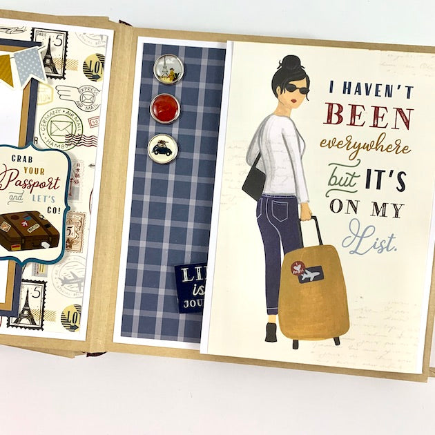 Our Greatest Adventure Travel Scrapbook Album Page with travel stamps, enamel brads, a blue plaid, a folding card, and a girl with her suitcase